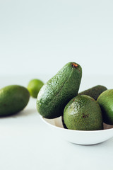 Fresh organic avocado in white ceramic bowl.