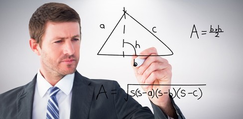 Composite image of serious businessman writing with marker