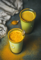 Golden milk with turmeric powder in glasses over dark background. Health and energy boosting, flu remedy, natural cold fighting drink. Clean eating, detox, weight loss concept