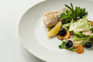 salad with black olives in a round plate on a white background