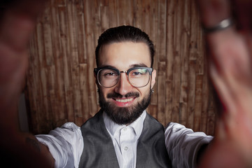 Funny stylish young guy doing selfie on a wooden background