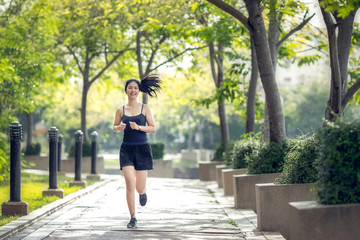 Fototapeta na wymiar Smiling asian beautiful woman running outdoors in park