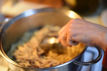 hand stirring in pot with pasta 