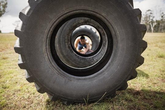 Man crawling through the tire during obstacle course