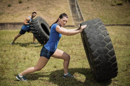 Man and woman flipping a tire during obstacle course