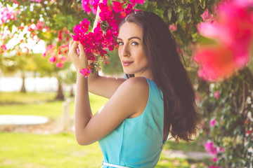 Naklejka premium Portrait of young woman posing near pink flowers