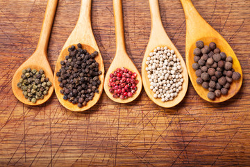 Black, white and red peppers in a wooden spoons