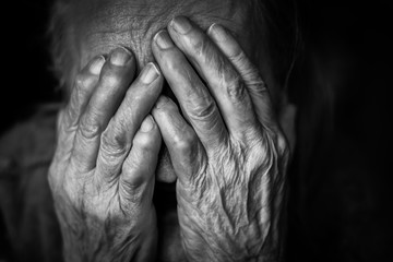  Closeup portrait depressed old woman covering her face with wrinkled hand