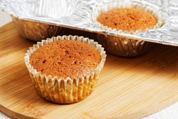 Homemade cupcakes in foil mold on white wooden table