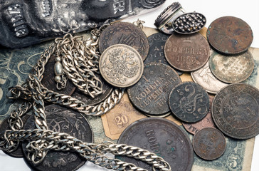 Antique silver, bar and silver and bronze coins and jewelry on old banknotes. On the white background.
