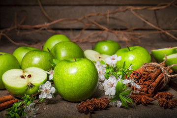 Green apples, cinnamon on a wooden background