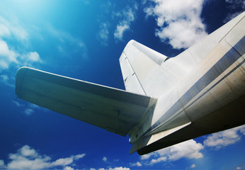 Tail of airplane with cloudy sky