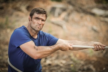 Man playing tug of war during obstacle course