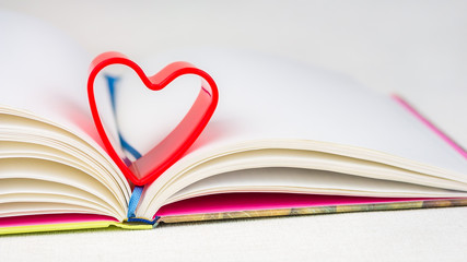 Red heart over diary book on white table