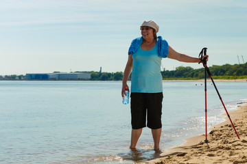 Senior woman practicing nordic walking on beach