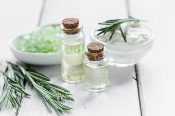 Rosemary essential oil in glass bottle in cosmetic set on table background