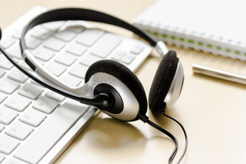 Office desk with headset and keyboard brown background