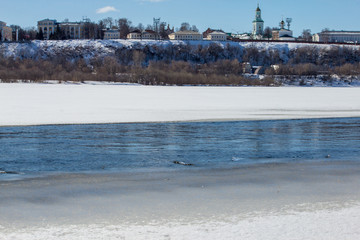 The river is covered with melting ice on a sunny spring day 