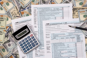 1040 tax from with us dollar banknote, pen and calculator.