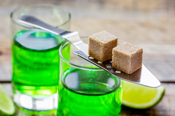 absinthe shots with lime slices and sugar on wooden table background