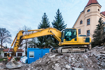 Obraz premium Schaufelbagger genießt Feierabend auf dem Bauschutt einer Baustelle