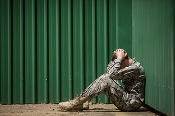 Frustrated military soldier sitting with hands on head