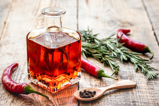 oil in carafe with spices and chili on wooden background