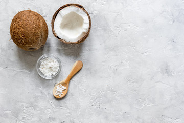 fresh coconut with cosmetic oil in jar on gray background top view