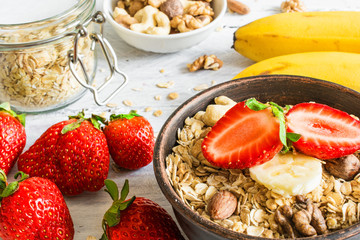healthy breakfast strawberry and banana muesli with oats, granola and nuts in a bowl