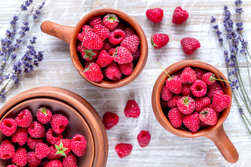 raspberry in pottery and lavender flowers on rustic background top view