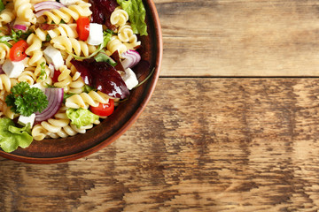 Cold delicious pasta salad on wooden table