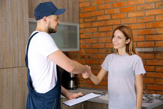 Plumber and woman shaking hands at home