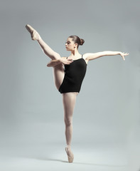 Naklejka premium Young beautiful ballerina dancing on light background