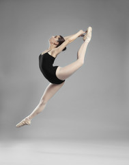 Obraz premium Young beautiful ballerina dancing on light background