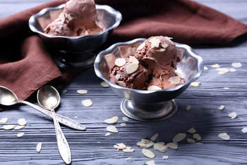 Tasty ice-cream with almond slices in bowl on wooden background
