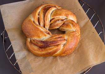 Fresh homemade sweet yeast bread swirl bun with cinnamon. On paper for baking. Selective focus