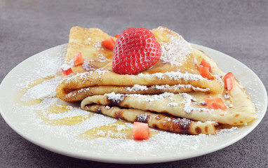 Two pancakes with strawberries on a plate.