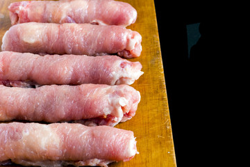 Raw meat rolls on wood board