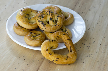 Baked fresh pretzels on white plate, heart and twisted knot shapes, covered with poppy seeds salt and caraway seeds