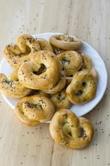 Baked fresh pretzels on white plate, heart and twisted knot shapes, covered with poppy seeds salt and caraway seeds