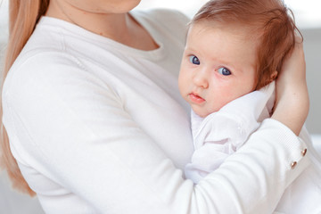 Young mother and newborn baby in white bedroom
