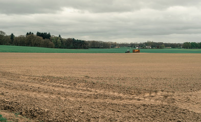 Fototapeta na wymiar Tractor in dutch hilly rural landscape with cloudy sky.