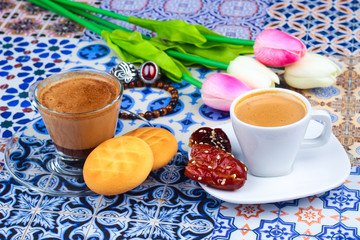 Cup of Arabian Coffee on an Oriental Colorful Background / Cup of Espresso on an Oriental Colorful Background with Flowers, Rings, and Tamr dates 