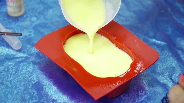 Hands pouring soap base to the red template