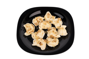 Fresh dumplings on a black plate seasoned with crispy onions. Ukraine