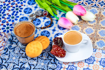 Cup of Arabian Coffee on an Oriental Colorful Background / Cup of Espresso on an Oriental Colorful Background with Flowers, Rings, and Tamr dates 