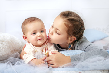 Girl kissing little sister. The concept of childhood and family.