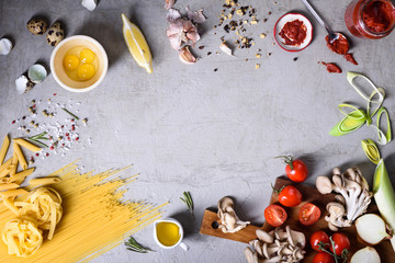 Italian pasta food frame, Spaghetti, linguine and penne with ingredients over grey concrete background. Top view, copy space, flat lay.
