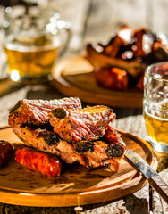 Grilled pork ribs and sausages on wooden table