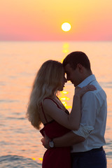 Beautiful young romantic couple on seaside in rays of rising sun